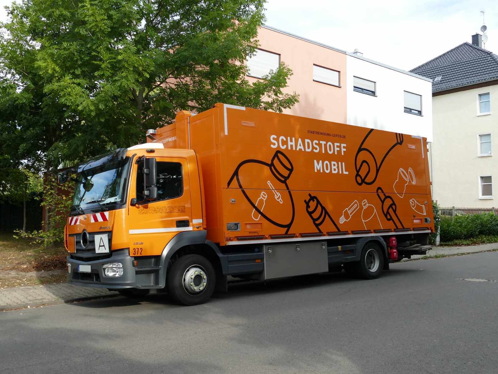 Ein Mitarbeiter im Schadstoffmobil nimmt einen Eimer Farbe von einem Herren entgegen
