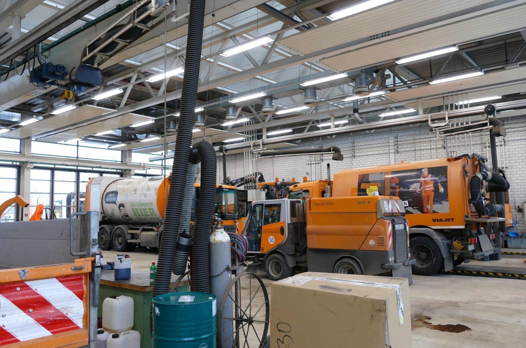 Eine Werkstatt mit vier Fahrzeugen (Kehrmaschine, Abfallsammelfahrzeug, Großkehrmaschine)