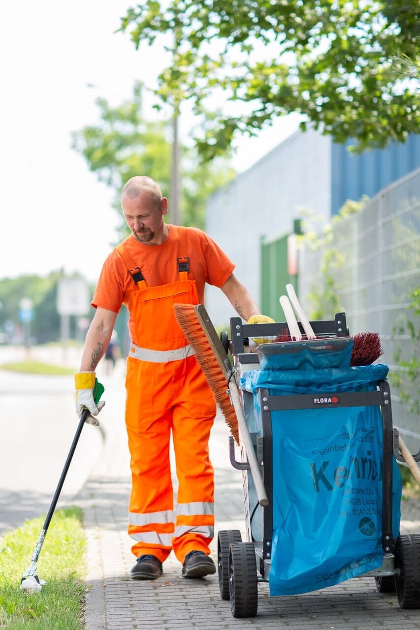 Ein Mitarbeiter der manuellen Straßenreinigung bei der Gehwegreinigung