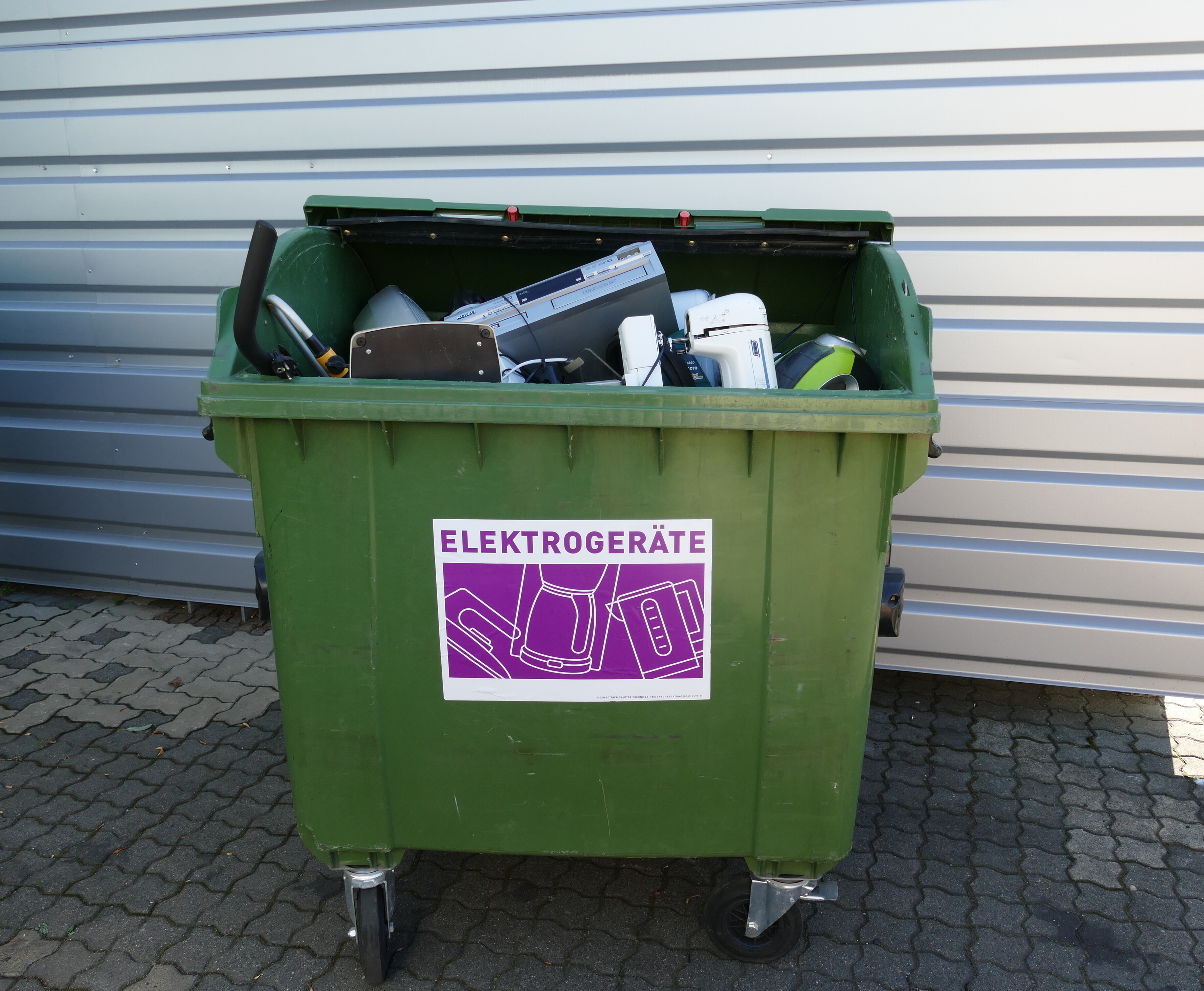 Ein gr&uuml;ner Elektroger&auml;te-Sammelcontainer, gef&uuml;llt mit Elektroaltger&auml;ten